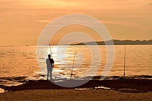 A silhouetted fisherman on the coast at sunset