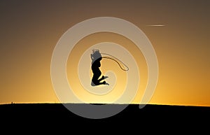 Silhouetted girl rope skipping in sunset