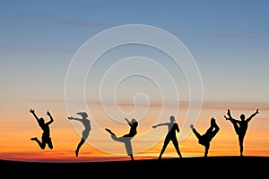 Silhouetted group tumbling and dancing in sunset