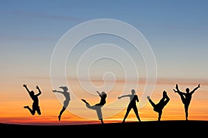 Silhouetted group tumbling and dancing in sunset photo