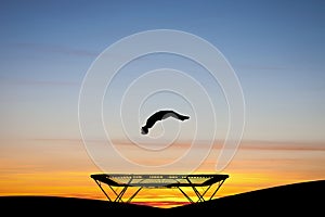 Silhouetted gymnast on trampoline
