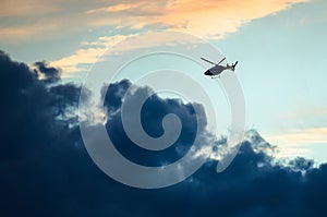 Silhouetted Helicopter Flying Across a Sunset Sky