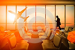 Silhouetted of man use mobile phone in airport at sunset. Business, connection and travel concept.