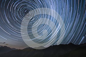 silhouetted mountains with circumpolar star trails in northern sky