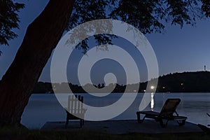 Silhouetted Muskoka Adirondack Chair on a Dock Beside a Lake