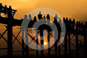 Silhouetted people crossing U bein bridge with sunset,The longest wooden bridge in Mandalay,Myanmar.