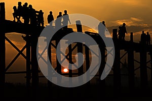 Silhouetted people crossing U bein bridge with sunset,The longest wooden bridge in Mandalay,Myanmar.