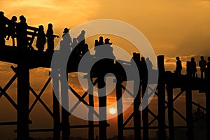 Silhouetted people crossing U bein bridge with sunset,The longest wooden bridge in Mandalay,Myanmar.