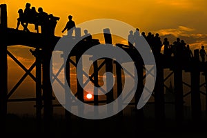 Silhouetted people crossing U bein bridge with sunset,The longest wooden bridge in Mandalay,Myanmar.