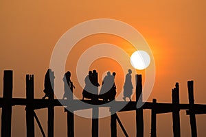 Silhouetted people on U Bein Bridge at sunset.