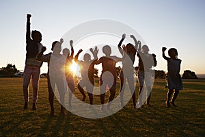 Silhouetted school kids jumping outdoors at sunset