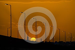 Silhouetted street lights along the road against the golden sunset sky, Riyadh, Saudi Arabia