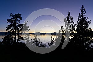 Silhouetted trees against the sunset over the mountains at Lake Tahoe