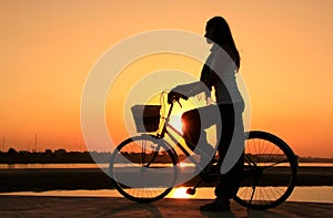 Silhouetted woman with bicycle at Mekong river