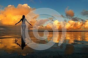 Silhouetted woman standing in a water at sunset on Taveuni Island, Fij