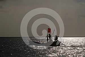 Silhouettes of Asian fishermen. Driving a traditional boat in the sea as the sun sets