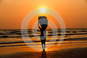 silhouettes of beautiful sexy young women surfer girls in bikinis with surfboards on a beach at sunset in sea, sport activity and