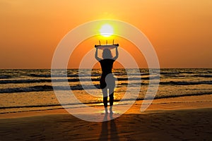 silhouettes of beautiful sexy young women surfer girls in bikinis with surfboards on a beach at sunset in sea, sport activity and