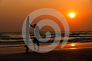 silhouettes of beautiful sexy young women surfer girls in bikinis with surfboards on a beach at sunset in sea, sport activity and