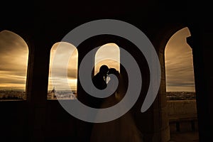 Silhouettes of bride and groom standing on night city background and tenderly looking at each other at sunset