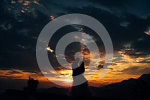 Silhouettes of the bride and groom who are embracing on Mount Lovcen overlooking the Bay of Kotor at sunset