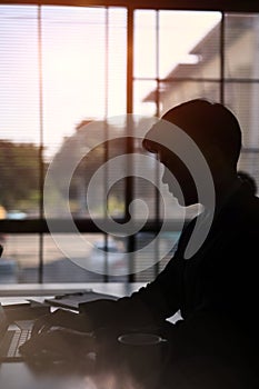 A businessman sitting near window and cocentrate working with computer tablet.