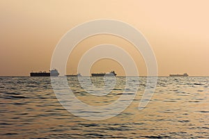 Silhouettes of cargo ships at sea at sunset