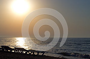 Silhouettes of chaise lounges on the beach of the sea