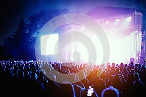 Silhouettes of concert crowd in front of bright stage lights.