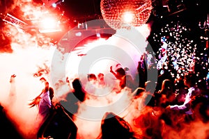 Silhouettes of concert crowd in front of bright stage lights with confetti