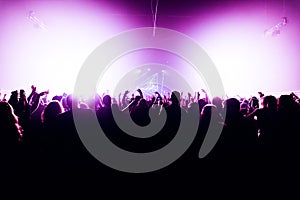 Silhouettes of concert crowd in front of bright stage lights with confetti