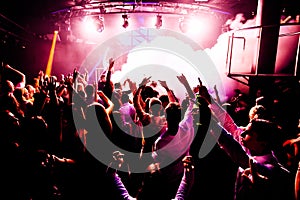 Silhouettes of concert crowd in front of bright stage lights with confetti