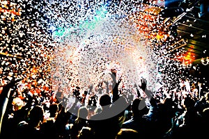 Silhouettes of concert crowd in front of bright stage lights with confetti photo