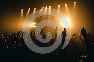 Silhouettes of concert crowd in front of bright stage lights. Unrecognized people in crowd. Copy space background. Crowd of fans a