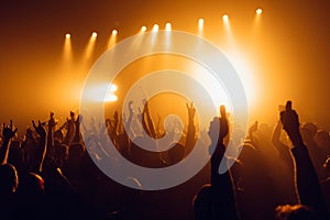 Silhouettes of concert crowd in front of bright stage lights. Unrecognized people in crowd. Copy space background. Crowd of fans a