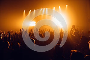 Silhouettes of concert crowd in front of bright stage lights. Unrecognized people in crowd. Copy space background. Crowd of fans a