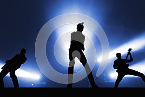 Silhouettes of cool rock band musicians on stage.