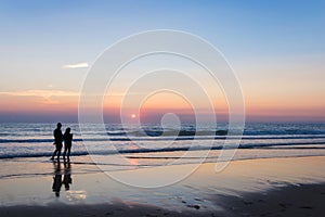 Silhouettes of a couple enjoying the sunset on the atlantic ocean