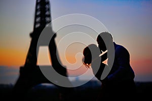 Silhouettes of a couple kissing in front of the Eiffel tower at sunrise in Paris, France