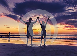 Silhouettes of couple in love at beach sunset celebrating freedom and love