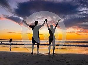 Silhouettes of couple in love at beach sunset celebrating freedom and love