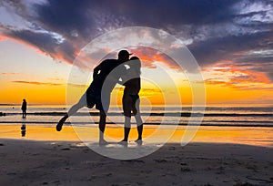 Silhouettes of couple in love kissing at beach sunset celebrating freedom and love