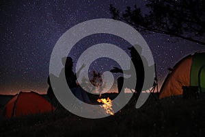 Silhouettes of couple near bonfire in evening. Camping season