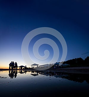 Silhouettes of crowd at seaside bar during sunset