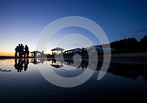 Silhouettes of crowd at seaside bar during sunset