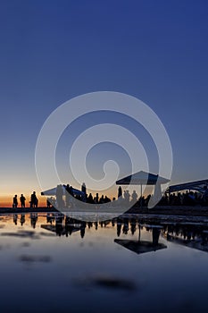 Silhouettes of crowd at seaside bar during sunset