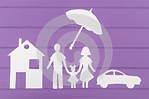 The silhouettes cut out of paper of man and woman with one girl under the umbrella, house and car near