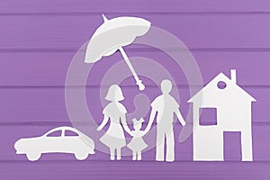 The silhouettes cut out of paper of man and woman with one girl under the umbrella, house and car near