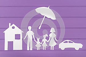 The silhouettes cut out of paper of man and woman with two girls under the umbrella, house and car near