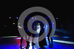 Silhouettes of dancing people in club in front of bright stage lights - disco concept.